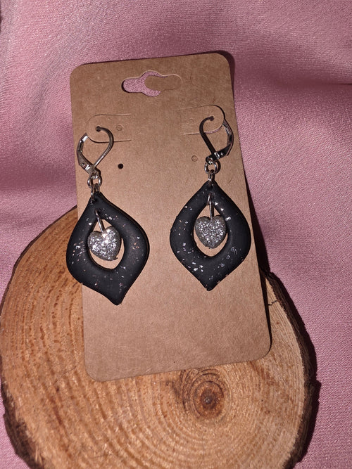 Handmade black clay open teardrop dangle earrings with silver glitter heart charm on silver leverback ear wires, on a kraft earring card