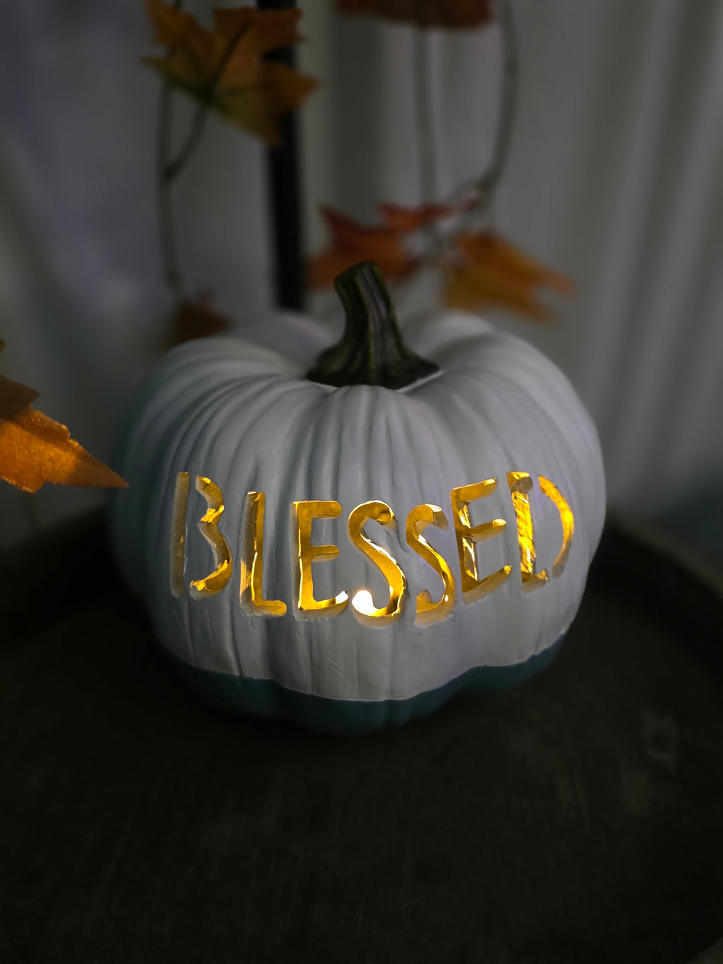 White and dusty blue carved pumpkin with BLESSED lettering glowing with warm candlelight