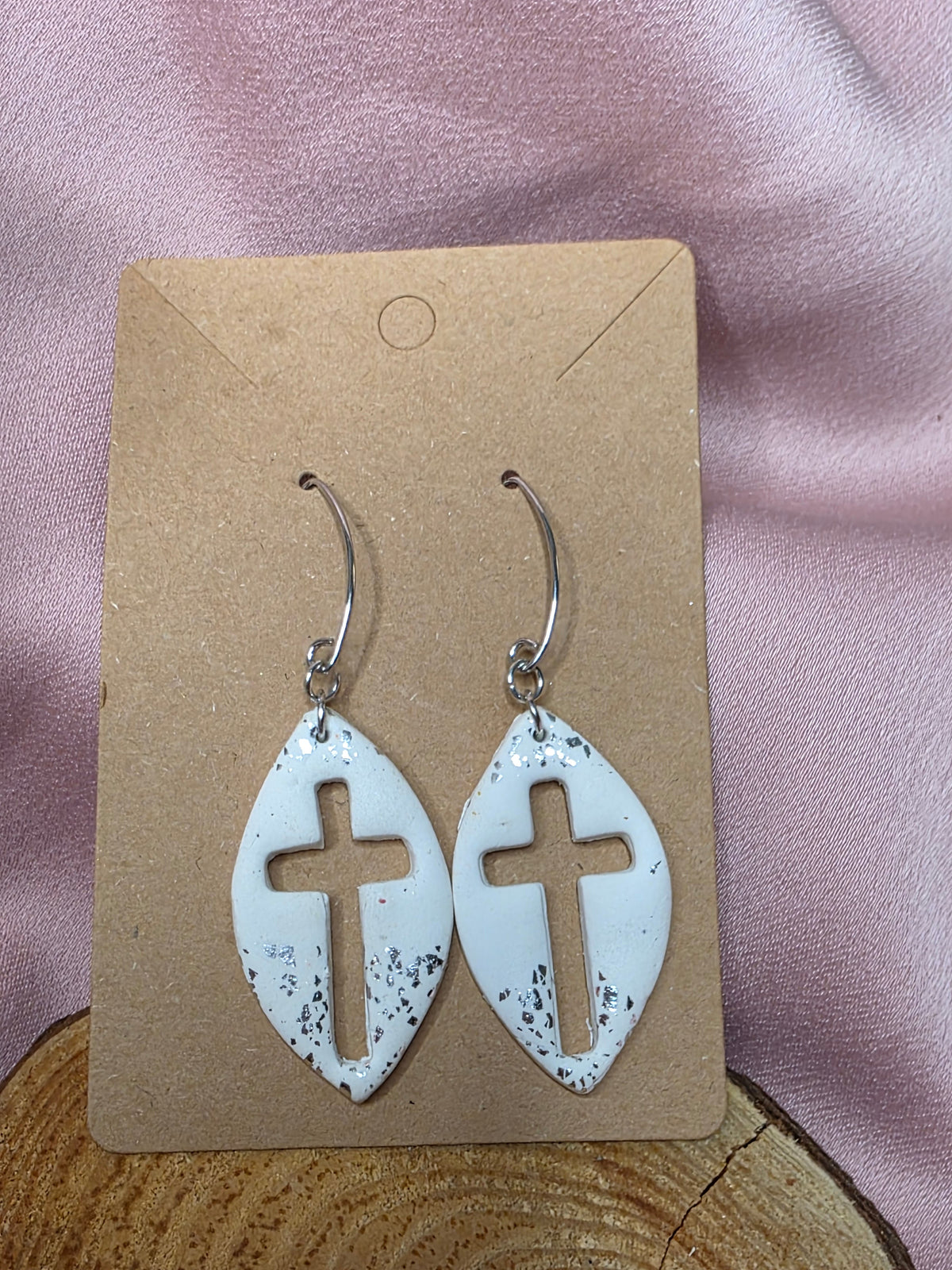 Pair of handmade white cross cutout dangle earrings on a display card